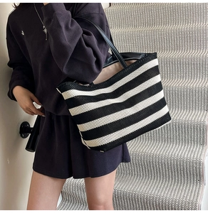 Détail d'un grand sac cabas rayé avec longues anses noires porté par un mannequin