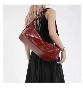 Détail du sac à bandoulière en cuir verni bordeaux avec rivets argentés sur la sangle
