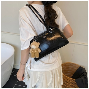Détail du sac oreiller noir brillant avec imprimé lettres et breloque ours en peluche