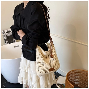 Detail showing hand-woven hollow knit tote bag with elegant brown leather shoulder strap