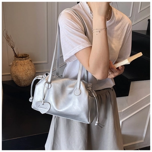 Silver pleated hobo bag with a heart-shaped charm shown on a shoulder for a stylish look