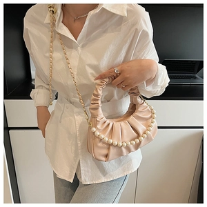 Close-up of pink ruched cloud bag featuring decorative pearl chain and long shoulder strap