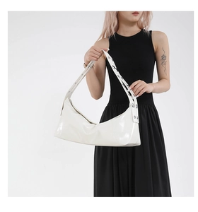 Close-up of white glossy hobo bag featuring a wide shoulder strap with metal grommet details