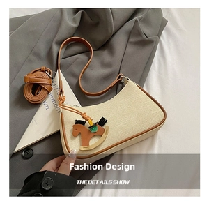 Detail of beige canvas crescent bag with brown leather trim and a small horse charm