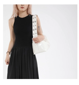 Close-up of a white leather shoulder bag with decorative silver metal studs on the strap