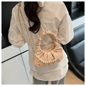 Detail of ruched cloud bag with pearl chain strap worn by a model in casual attire