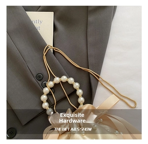 Dettaglio della collana d'oro con pendente di perle su una giacca di classe grigia