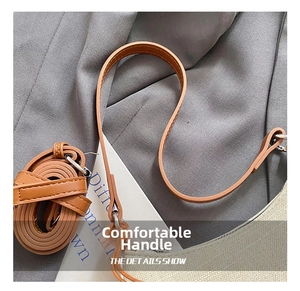 Detail showing the brown leather handle, strap, and beige textured fabric with neat stitching