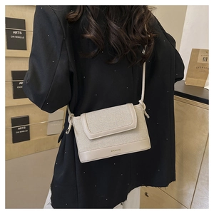Detailed view of beige textured fabric crossbody bag with leather trim on model