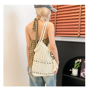 Detail of off-white crochet tote bag featuring intricate hollow patterns and dark beads