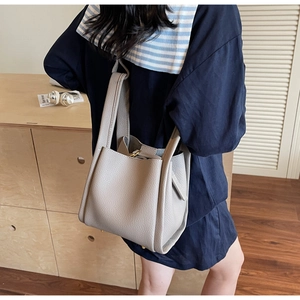 Detailed view of grey litchi grain leather bucket bag with metallic gold padlock detail