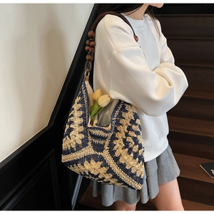 Detail of woven tote bag with blue floral patterns and brown beaded wooden handle