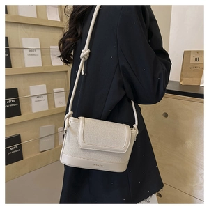 Detail of beige crossbody bag featuring canvas texture, leather trim and BAIKOU logo