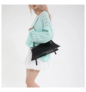 Detail of black glossy patent leather shoulder bag with adjustable silver buckle