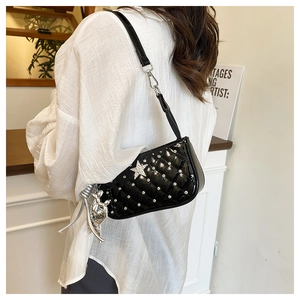 Detail of black quilted patent leather bag featuring silver star and metal charms