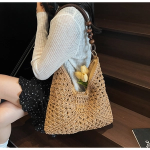 Detail of bohemian straw tote bag featuring intricate crochet patterns and wood bead strap