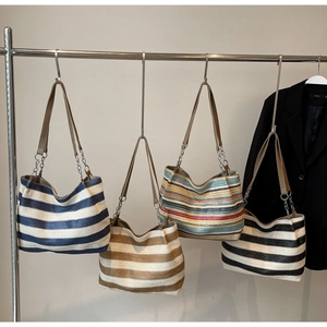 Detail of woven straw tote bags with striped patterns and leather shoulder straps