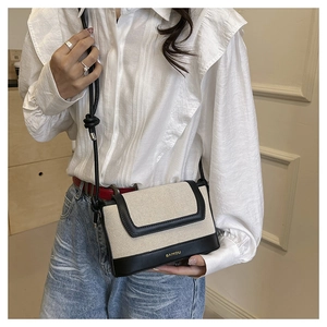 Detail showing the canvas and leather contrast strap on a white and black square handbag