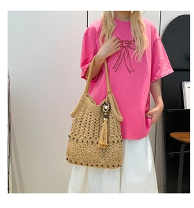 Detail of hand-woven tote bag showing intricate cut-out patterns and fringe tassel