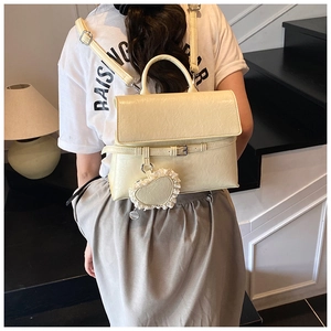 Detail of cream white PU leather backpack featuring lace heart pendant and flap closure