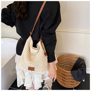 Macro detail of beige woven tote bag featuring brown leather straps and wooden bead accents