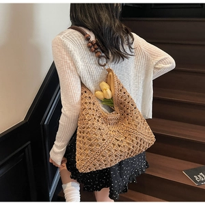 Detail of hand-woven straw tote with hollow diamond patterns and dark wood bead strap