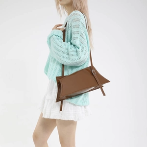 Sac fourre-tout minimaliste en cuir brillant marron foncé porté par une femme mannequin