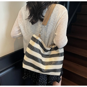 Détail du sac cabas tissé avec rayures noires et blanches et bandoulière chaîne et cuir