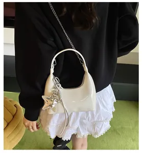 Detail of white patent leather underarm bag with silver chain and star charm ornament