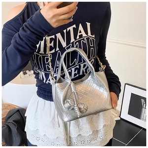Détail du sac seau tissé argenté avec texture métallique et nœuds décoratifs