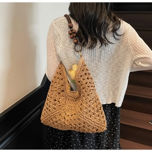 Close-up of a hollow-out woven tote bag featuring dark wooden bead shoulder straps