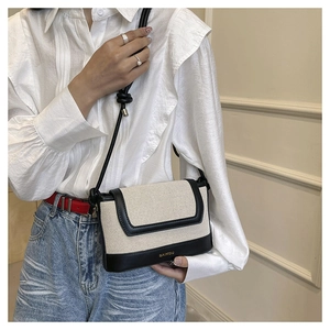 Close-up of stylish contrast canvas crossbody bag showing golden logo and stitching detail