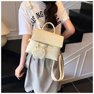 Detail of minimalist cream backpack with lace heart pendant and textured leather finish
