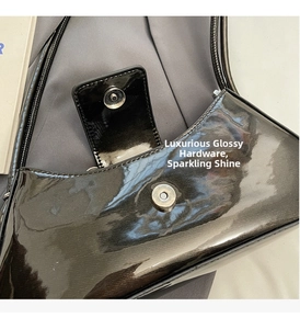Détail du fermoir magnétique en métal sur le sac à bandoulière en cuir verni noir