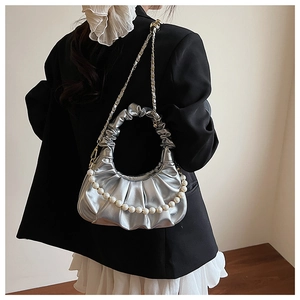 Silver pleated dumpling bag with pearl handle and metal chain on a model in black blazer