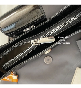 Détail de la fermeture éclair en métal argenté sur un sac en cuir verni noir brillant