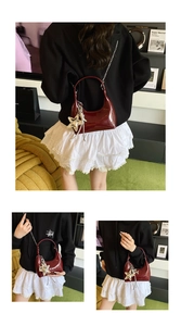Detail of glossy burgundy patent leather half-moon bag with star pendant and chain strap