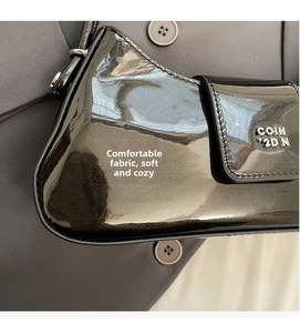 Détail du sac bandoulière en cuir verni noir avec logo métallique et finition brillante