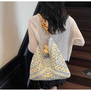 Detail of blue and yellow woven crochet tote bag with wooden bead straps for summer beach