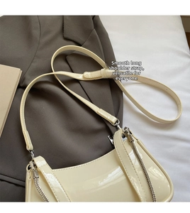 Détail du sac baguette en cuir verni crème avec chaîne argentée et bandoulière réglable