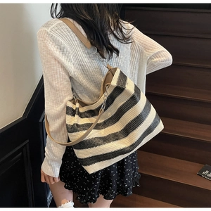 Detail of a large woven tote bag with black and white stripes and chain strap