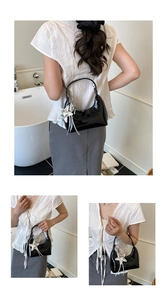 Close-up of black patent leather hobo bag featuring a silver star charm and glossy finish