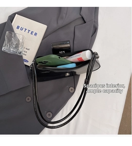 Intérieur spacieux du sac baguette en cuir verni noir contenant portefeuille et cosmétiques