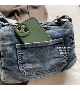 Detail view of the back pocket on a vintage washed denim crossbody bag for phone storage