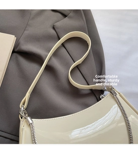 Détail du sac baguette en cuir verni crème avec d'élégantes bretelles en chaîne argentée