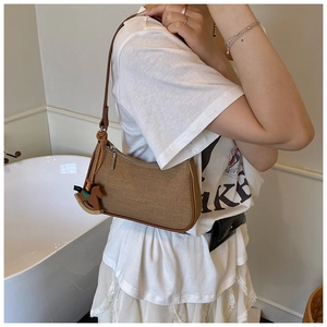 Detailed view of canvas underarm bag with leather trim and wooden horse charm