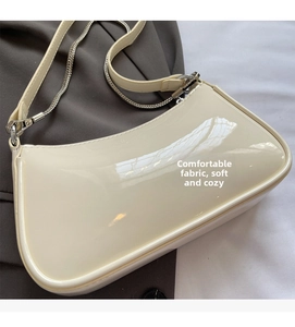 Détail du sac baguette en cuir verni beige avec chaîne argentée et finition brillante