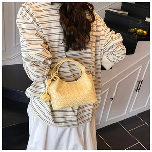 Vue détaillée arrière d'un sac seau tressé jaune beurre avec nœud et bandoulière chaîne dorée