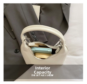 Detail view of the interior space in a cream glossy crescent bag with small essentials