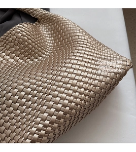 Detailed close-up of champagne gold woven faux leather texture and cross pattern